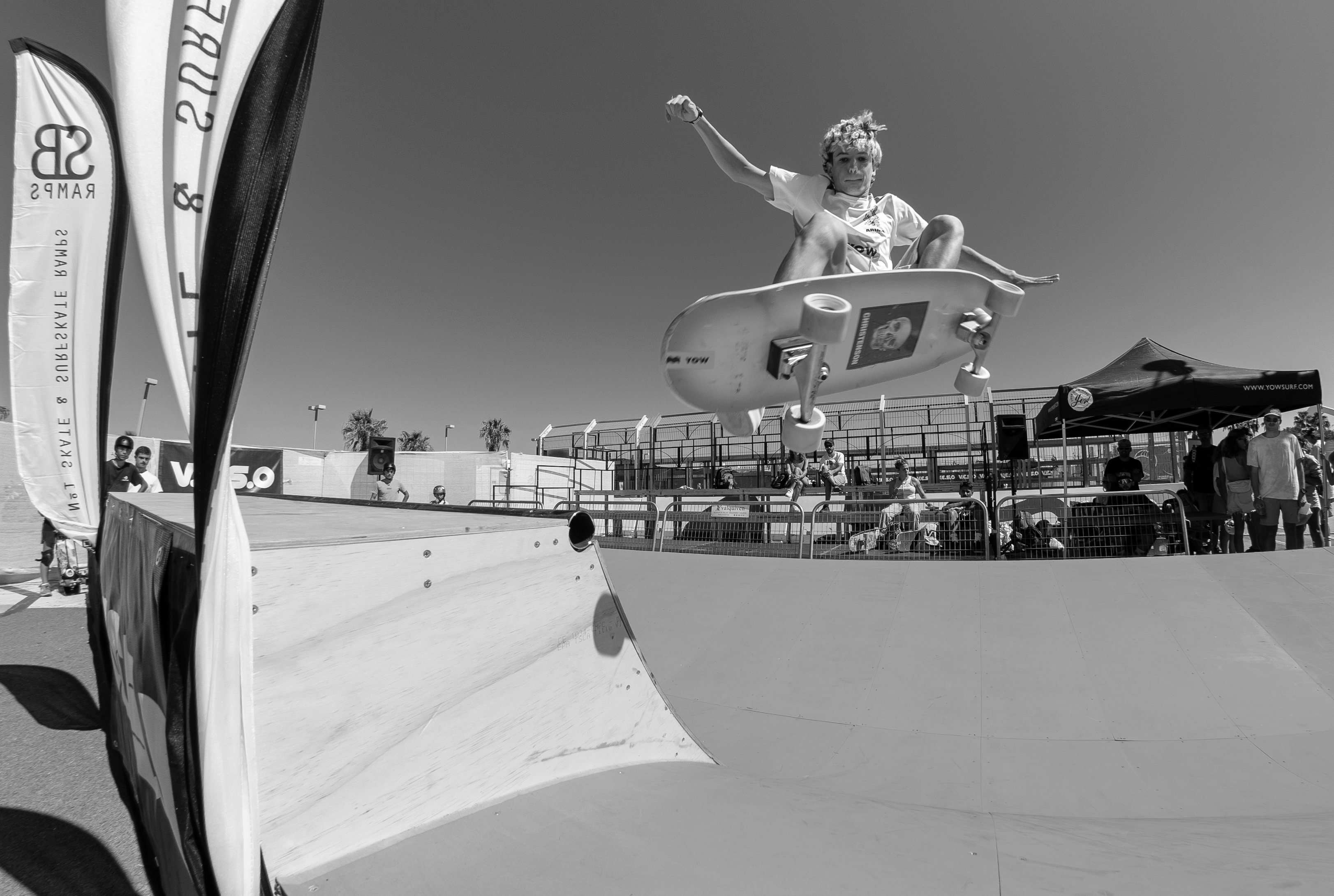 Skater aéreo en URBNS Valencia. Clases de surfskate. Logo VESO y público al fondo.